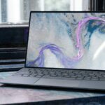 A laptop displaying an abstract blue and purple pattern on a marble surface